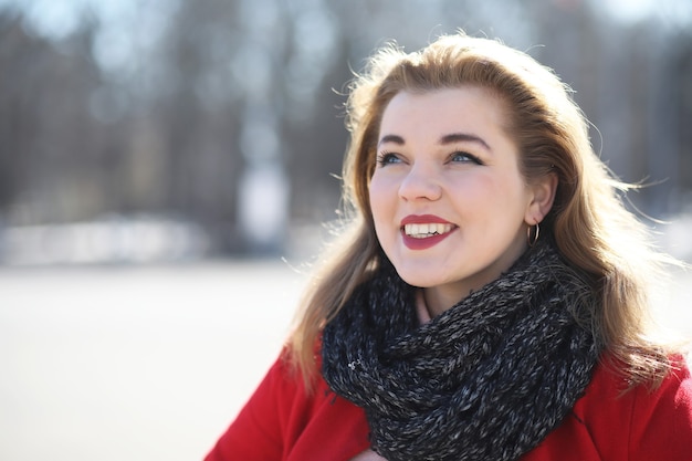 Pretty girl on a walk in a red coat in the city