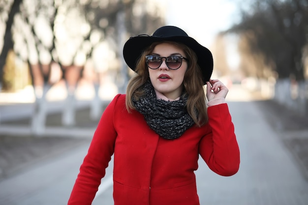 Pretty girl on a walk in a red coat in the city