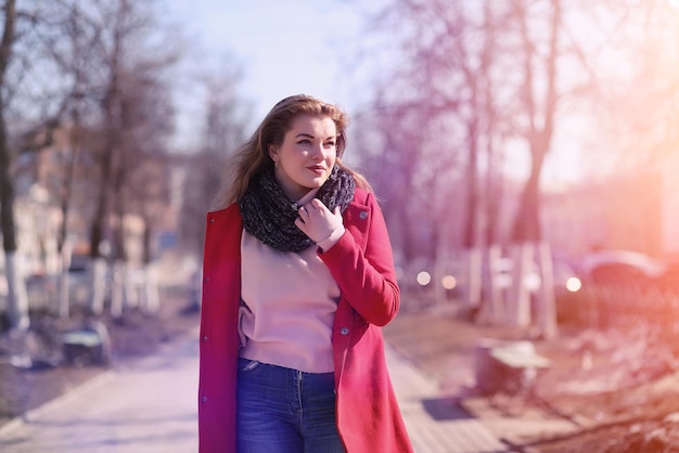 Pretty girl on a walk in red coat in the city