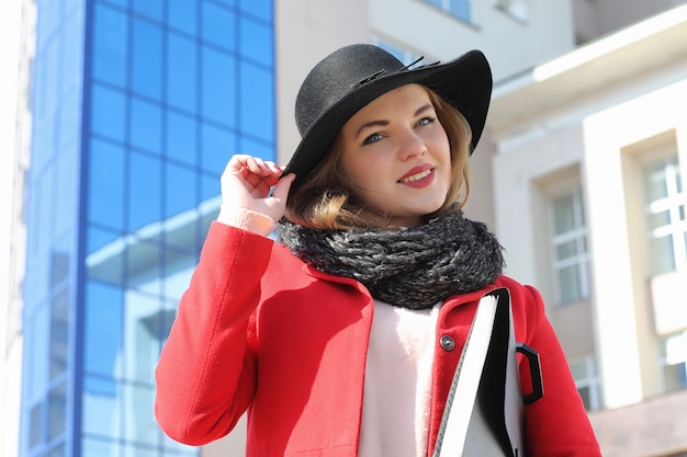 Pretty girl on a walk in red coat in the city