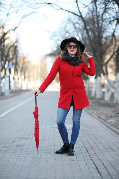 Pretty girl on a walk with red umbrella in the city