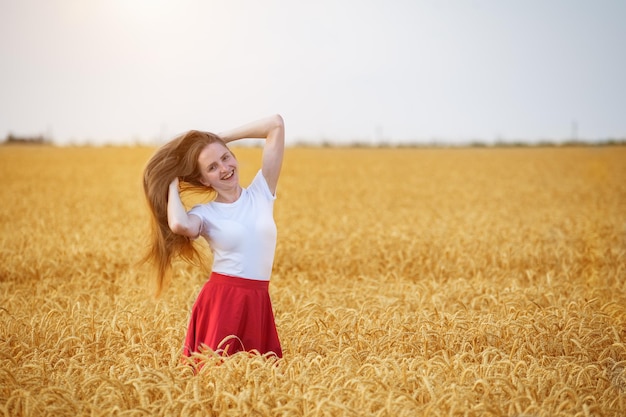 Pretty girl walks in wheat field Happy young woman with long beautiful hair Weekend in village