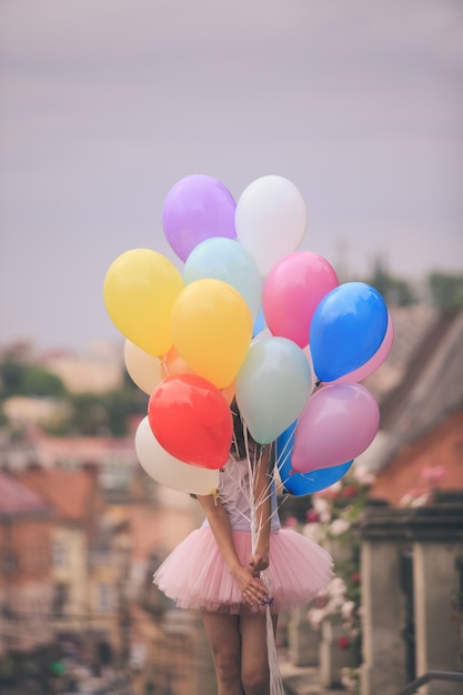 Photo pretty girl with big colorful latex balloons posing in the street of an old town