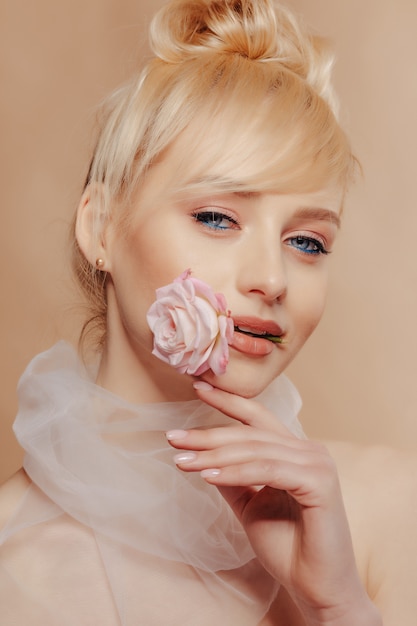 Pretty girl with blond hair, fashion shooting, rose, simple background