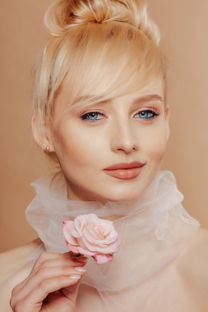 Pretty girl with blond hair, fashion shooting, rose, simple background