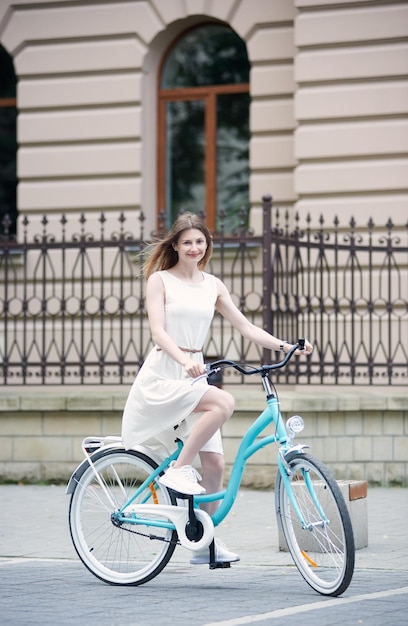 Bella ragazza con una bici blu