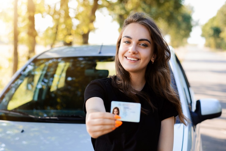 Photo pretty girl with cheerful smile standing near the car and showing driving license to the front. woman expresses her happiness after passing the driving exam.