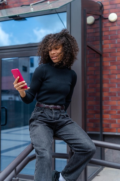 pretty girl with curly hair using mobile phone in the city female blogger using smart phone
