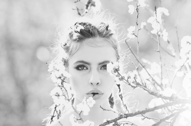 Pretty girl with fashionable makeup among spring blooming cherry flowers