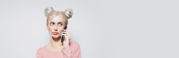 Pretty girl with hair buns talking on smartphone on white Panoramic banner