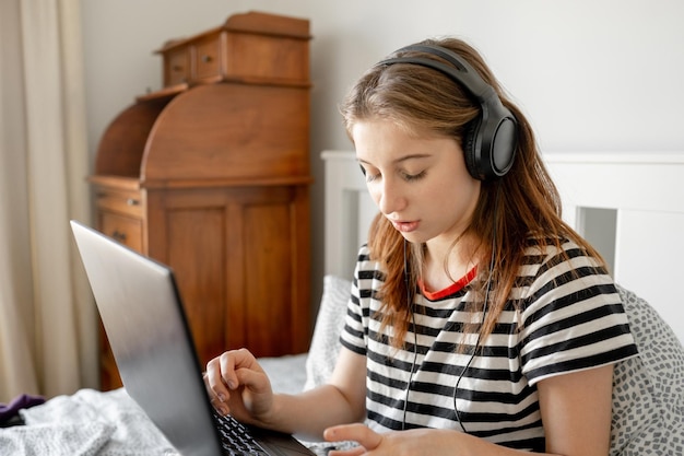 Bella ragazza con cuffie e laptop a letto