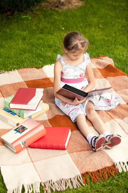 Photo pretty girl with photo album sitting on plaid at park