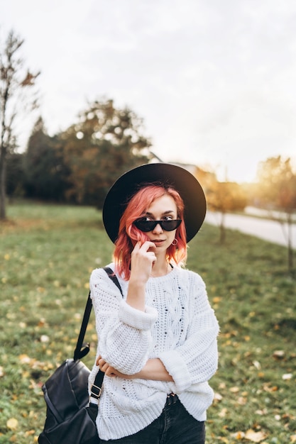 Pretty girl with red hair and hat relaxing in the park, autumn time.