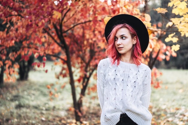 Pretty girl with red hair and hat walking in the park, autumn time.