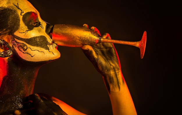 Pretty girl with skeleton makeup holds glass