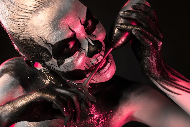 Pretty girl with skeleton makeup holds glass