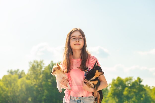 自然に 2 匹のチワワ犬を持つかわいい女の子。ペットの犬を腕に抱えた 10 代の少女。