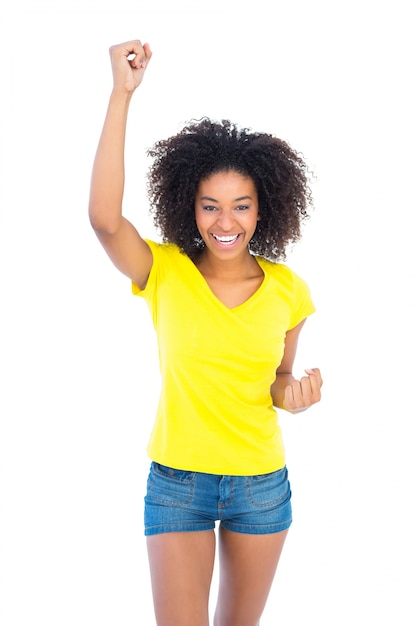 Pretty girl in yellow tshirt and denim hot pants cheering at camera