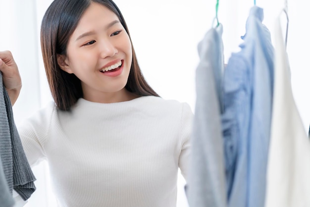 Pretty happiness asian woman shopping with fun chooing cloths dress in store white room background