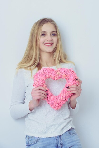 Довольно счастливая девушка с розовым плетеным сердцем на день святого валентина