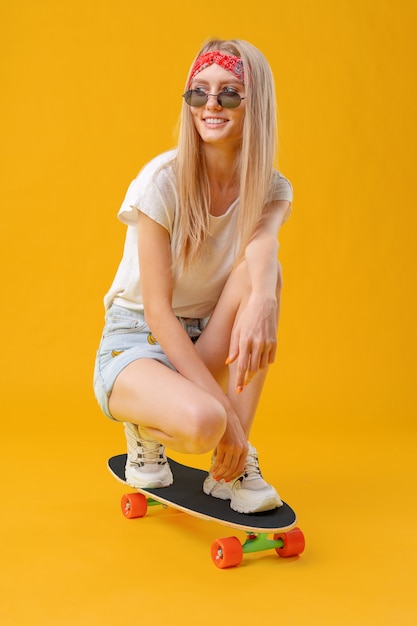 Pretty happy woman casually dressed sits on her skateboard 