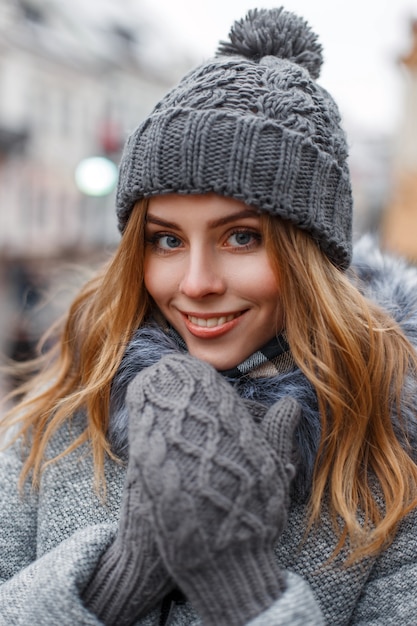 Donna abbastanza felice in un cappello lavorato a maglia e guanti di lana grigi