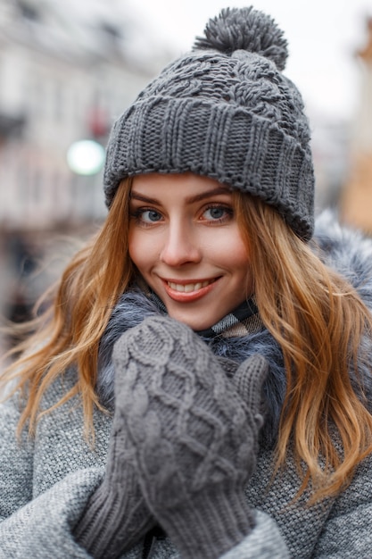 Pretty happy woman in a knitted hat and a gray woolen mittens