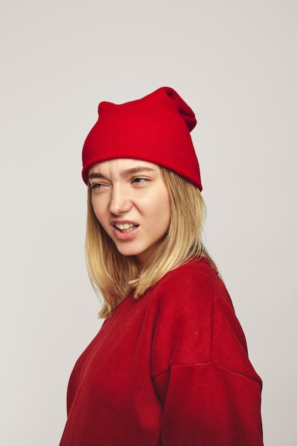 Una bella ragazza hipster ringhia come una tigre che indossa un cappello rosso alla moda e