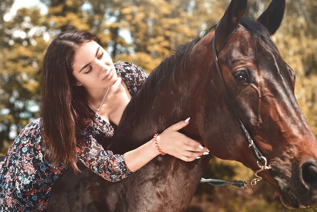 Bella bruna ispanica che abbraccia il suo cavallo mentre lo cavalca nella foresta. amo il concetto di animali. amo i cavalli