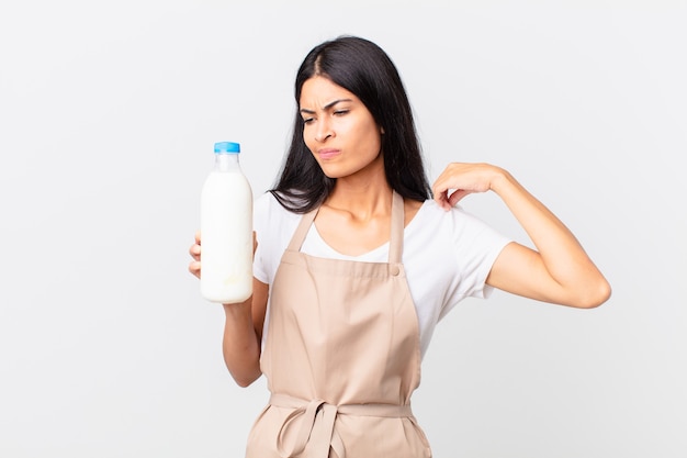 Pretty hispanic chef woman feeling stressed, anxious, tired and frustrated and holding a milk bottle