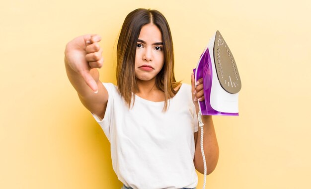 Pretty hispanic girl feeling crossshowing thumbs down housekeeping concept