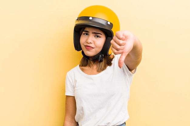 Pretty hispanic girl feeling crossshowing thumbs down motorbike concept