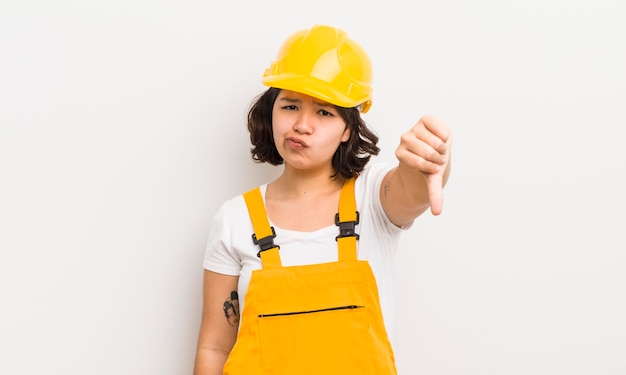 Pretty hispanic girl feeling crossshowing thumbs down worker concept