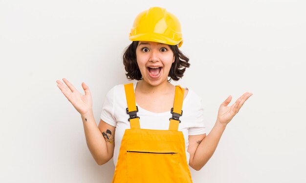 Pretty hispanic girl feeling happy and astonished at something unbelievable worker concept