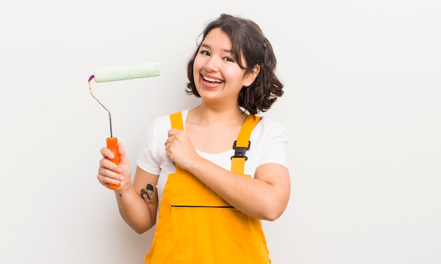 Pretty hispanic girl feeling happy and facing a challenge or celebrating painting home concept