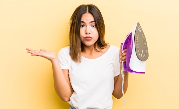 Pretty hispanic girl feeling puzzled and confused and doubting housekeeping concept