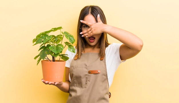 手植物のコンセプトでショックを受けた怖いまたは恐怖のカバー顔を探しているかなりヒスパニック系の女の子