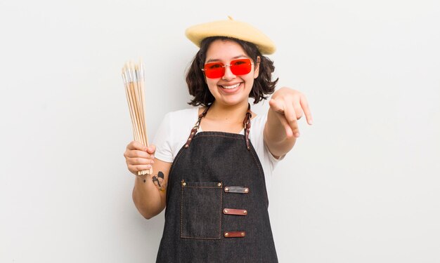 Pretty hispanic girl pointing at camera choosing you art student concept