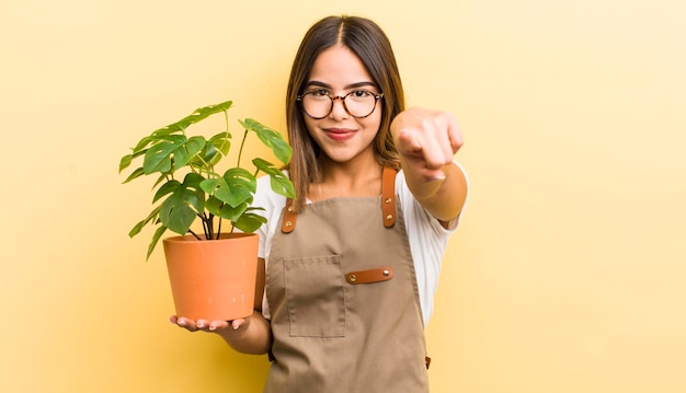 Pretty hispanic girl pointing at camera choosing you plant concept