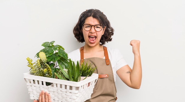 Pretty hispanic girl shouting aggressively with an angry expression plants concept