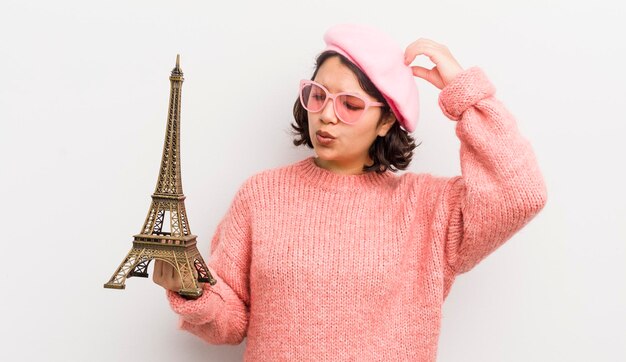 Foto bella ragazza ispanica sorridente felicemente e sognare ad occhi aperti o dubitare del concetto di parigi