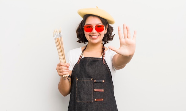 Pretty hispanic girl smiling and looking friendly showing number five art student concept