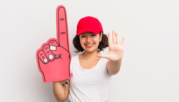 Photo pretty hispanic girl smiling and looking friendly showing number five number one hand fan concept