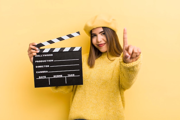 Pretty hispanic girl smiling and looking friendly showing number one cinema concept