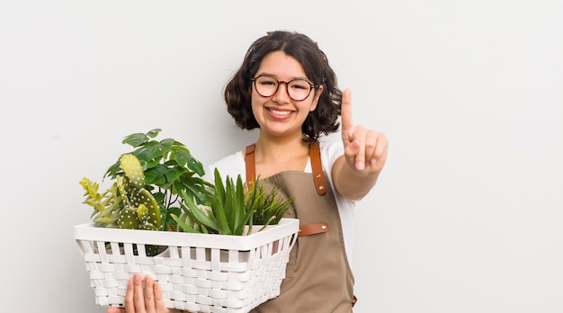 Pretty hispanic girl smiling and looking friendly showing number one plants concept