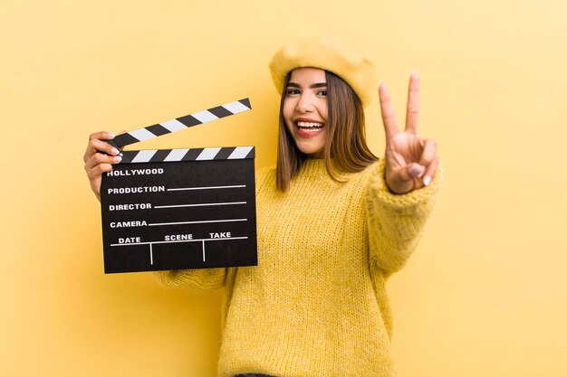 Pretty hispanic girl smiling and looking friendly showing number two cinema concept