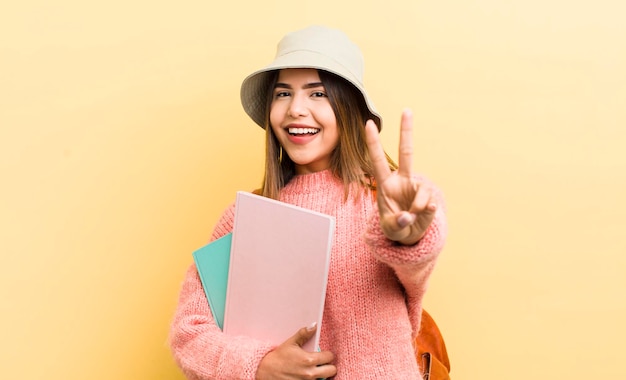 Pretty hispanic girl smiling and looking friendly showing number two student concept