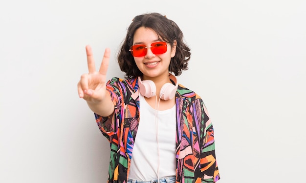 Pretty hispanic girl smiling and looking friendly showing number two teenager concept