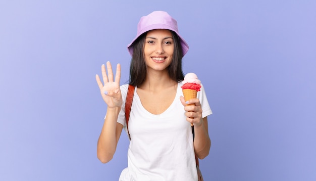 Pretty hispanic tourist smiling and looking friendly, showing number four and holding an ice cream