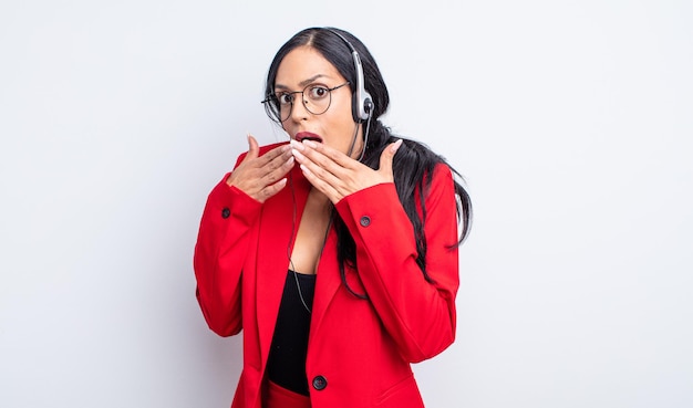 Pretty hispanic woman covering mouth with hands with a shocked. telemarketing concept